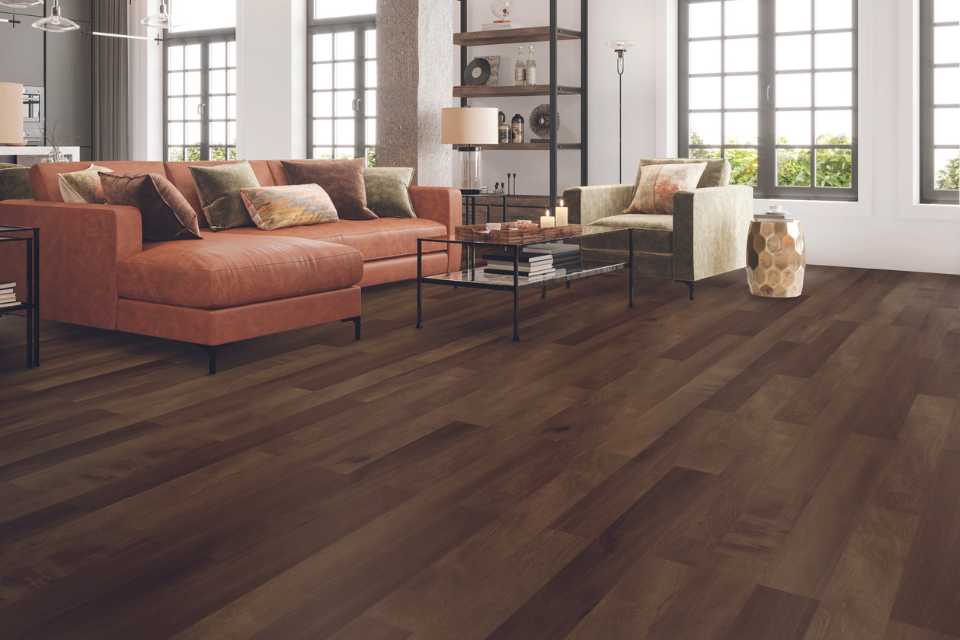 dark earth toned wood look luxury vinyl in living room with red leather couch